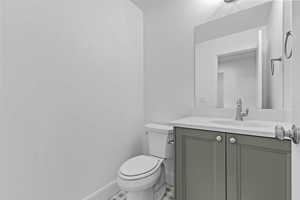 Vanity with light gray shaker-style cabinetry, white countertop, and integrated sink