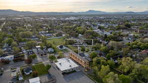 Aerial perspective showcasing a residential neighborhood with mature trees and mountain ranges in the distance