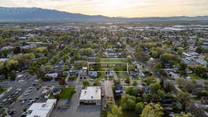 Aerial perspective of Logan, UT, showcasing a residential area with mature trees and visible mountain ranges in the distance