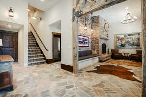 Expansive room featuring irregular flagstone flooring, a brick fireplace with stone hearth, exposed wood beams, and a built-in bench