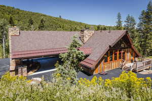 Wood-sided home with a multi-gabled roofline, stone chimney, and an attached carport