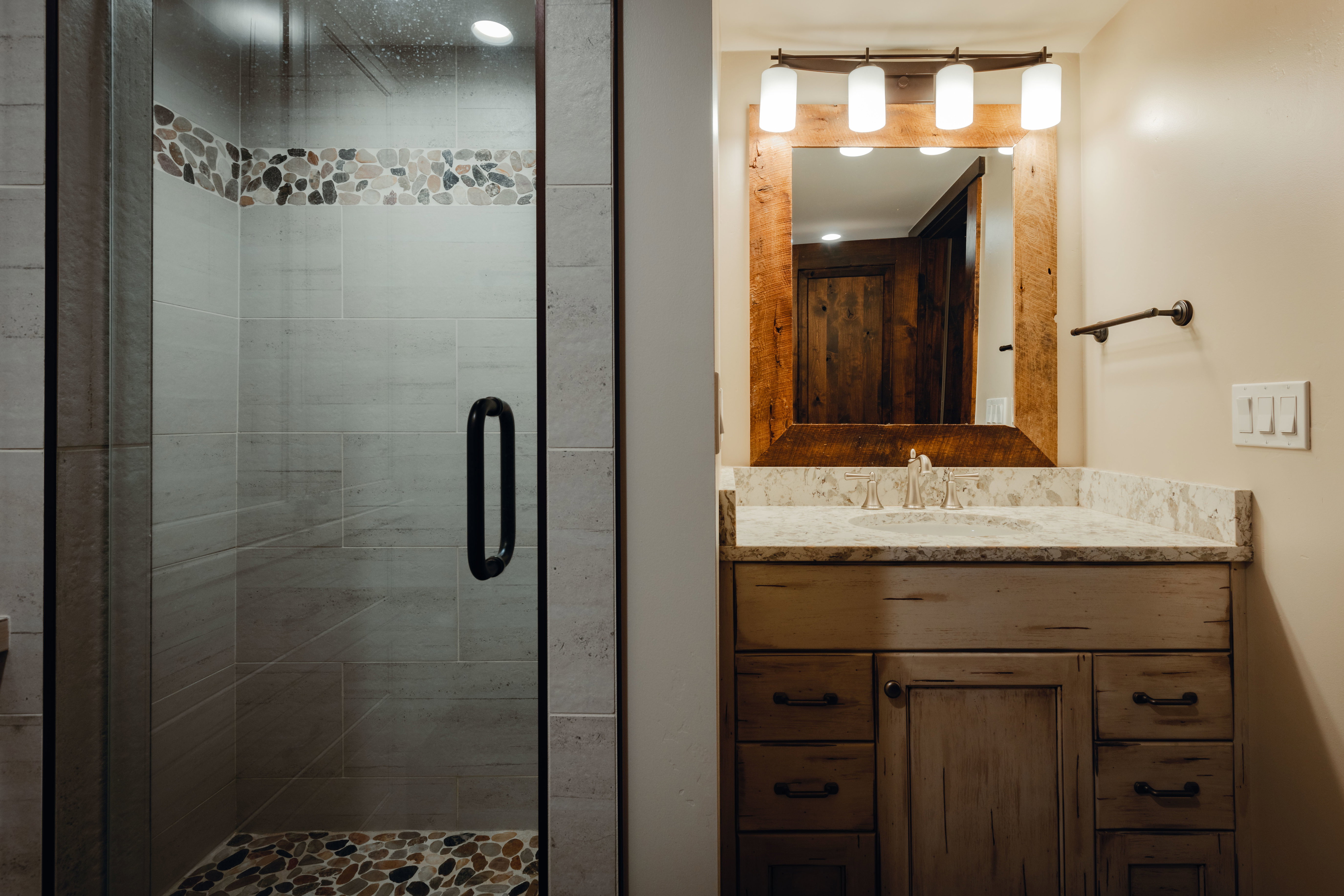 Glass-enclosed shower with pebble tile floor and accent band