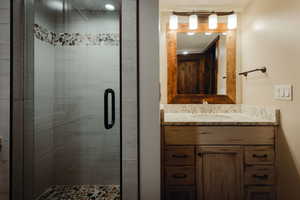 Glass-enclosed shower with pebble tile floor and accent band