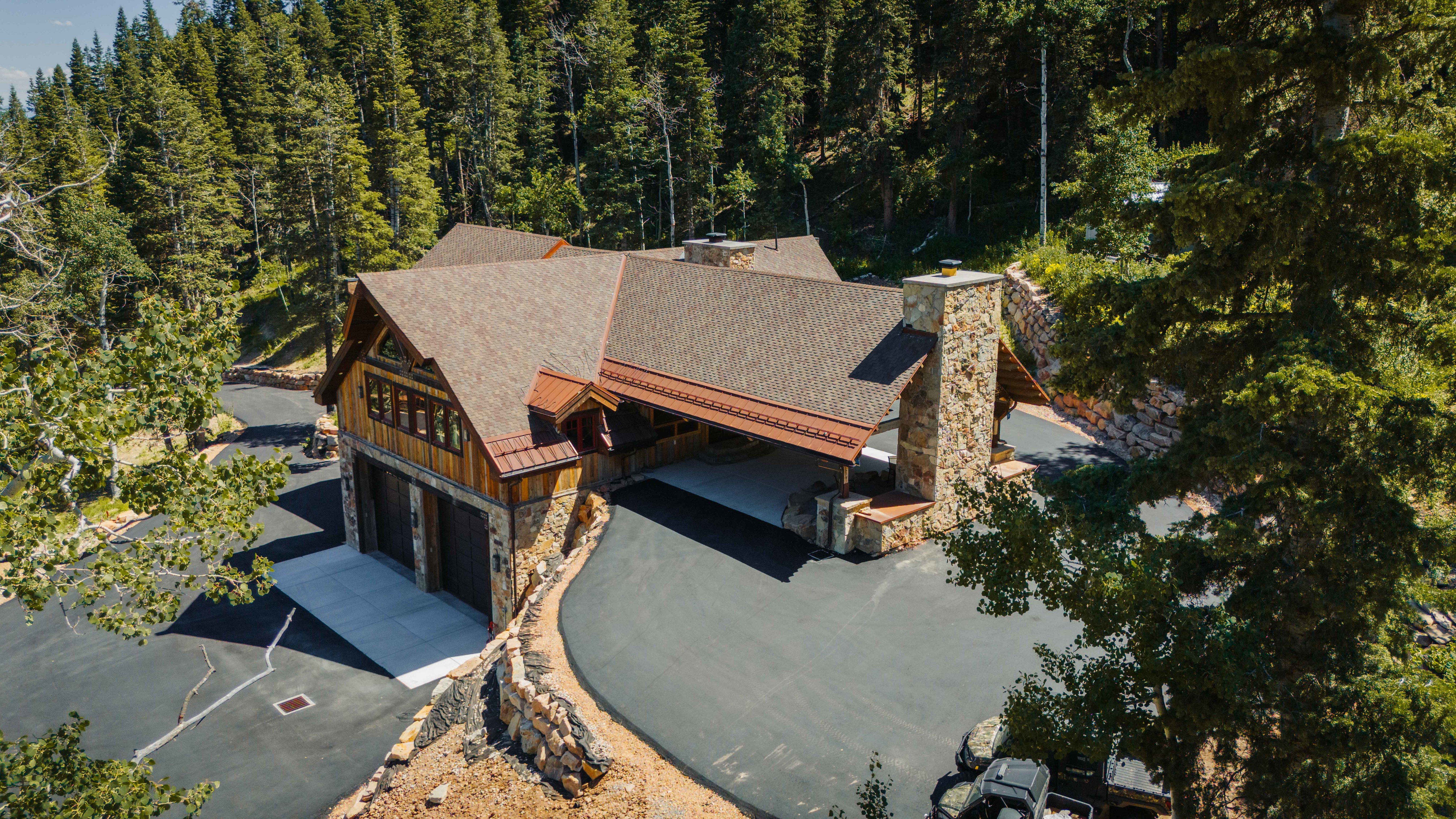 Expansive property featuring a stone and wood-sided architectural style, a multi-car garage, and a large paved driveway