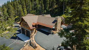 Expansive property featuring a stone and wood-sided architectural style, a multi-car garage, and a large paved driveway