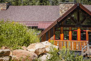 Wood-sided exterior featuring large windows with red trim and a stone chimney