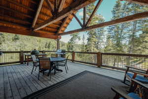 Expansive covered deck featuring a natural wood ceiling with exposed beams, wood-finish decking, and a metal grid railing