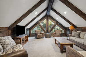 Vaulted ceilings with exposed wood beams, expansive triangular windows, recessed lighting, and wood-paneled walls