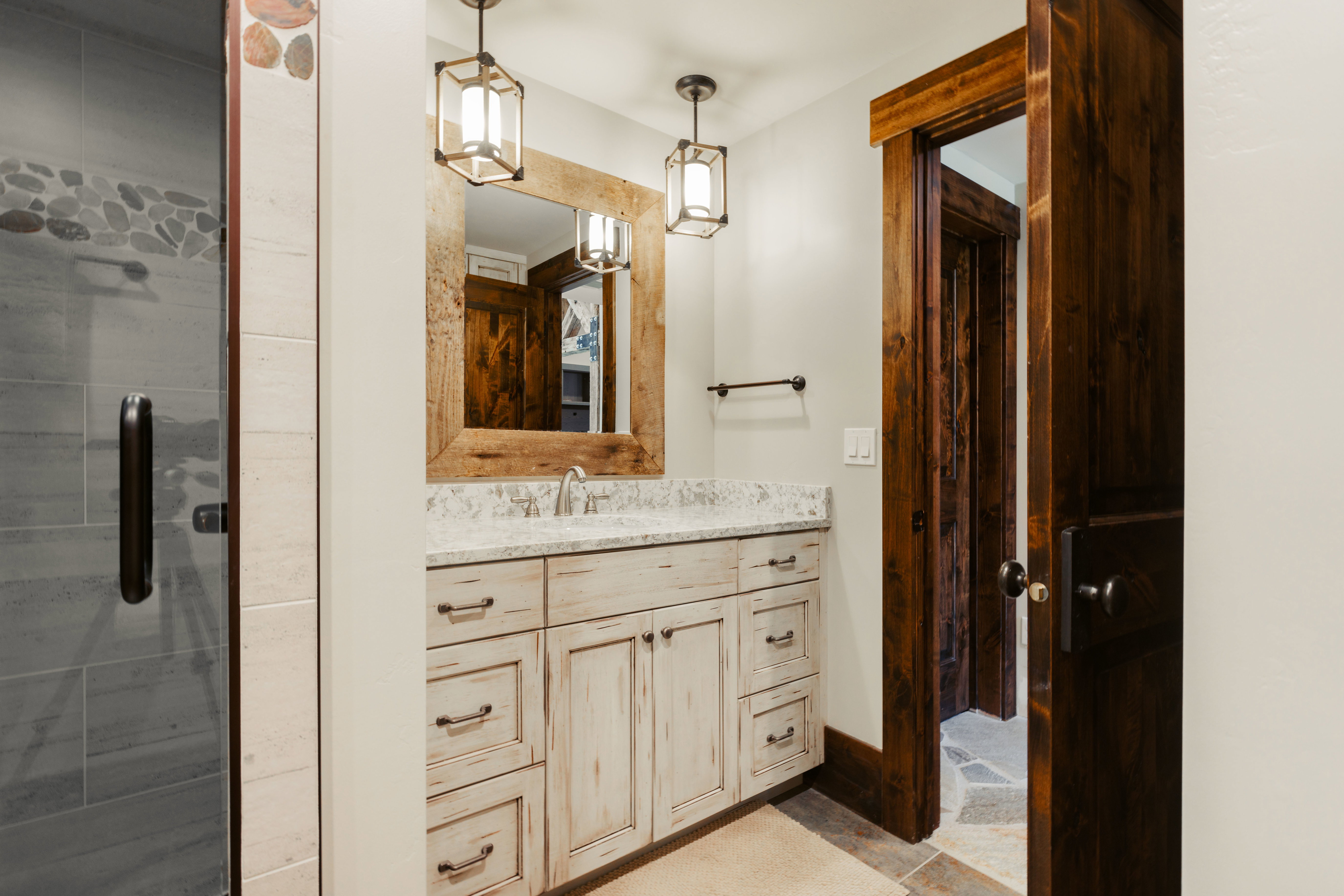 Whitewashed vanity with a light-toned countertop and dual pendant lighting fixtures
