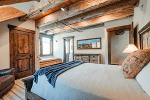 Exposed wood-beam ceiling with integrated lighting, rustic wood-paneled door, and a built-in window bench