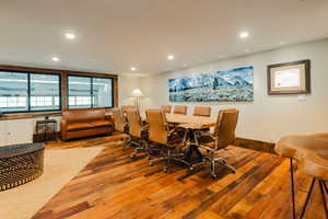 Spacious room featuring rich wood-finish flooring, recessed lighting, and large windows with horizontal blinds