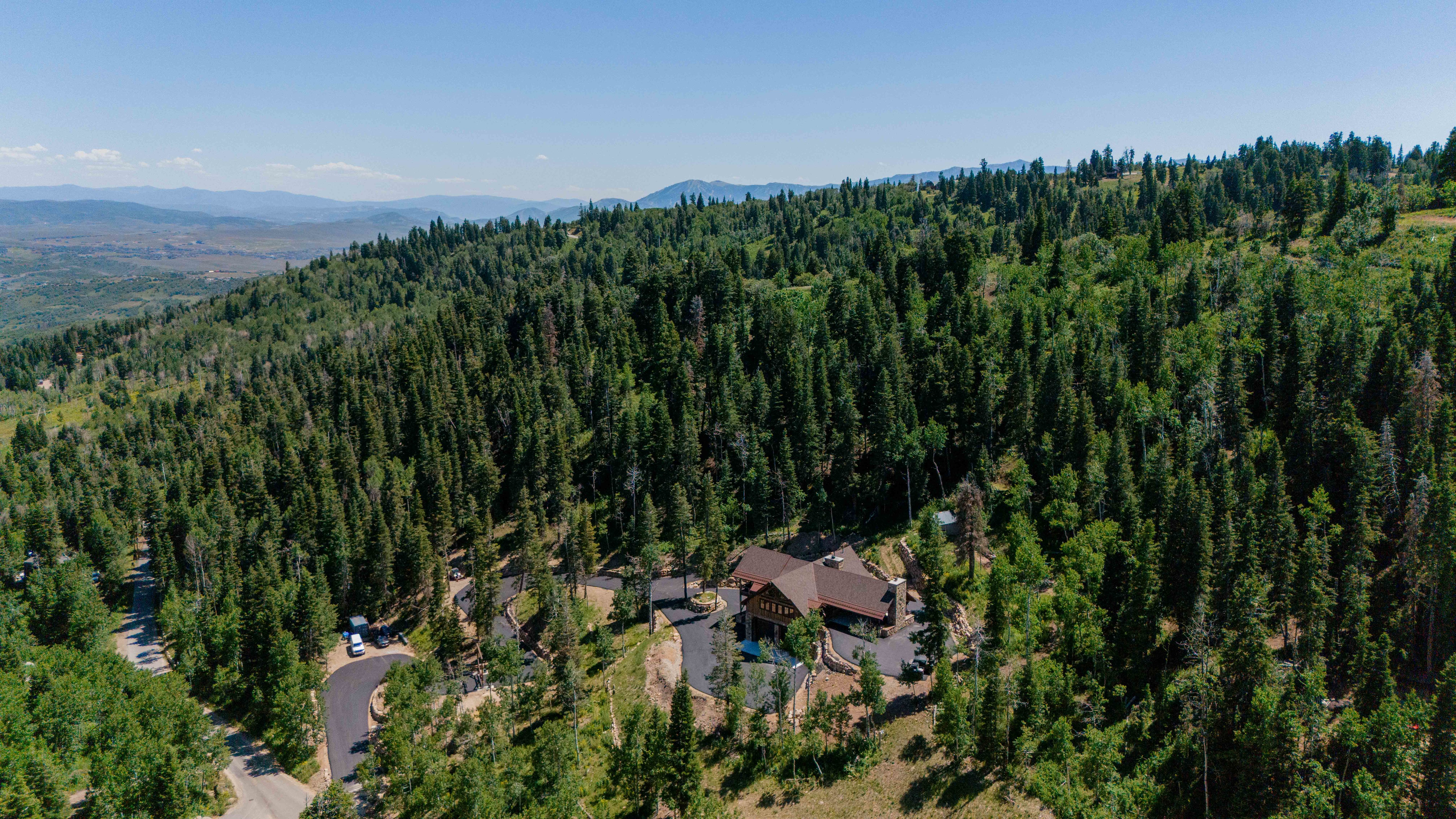 Mountain-style residence nestled within a dense forest, featuring a prominent brown roof and stone accents