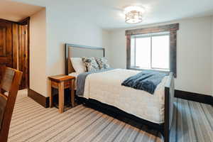 Bedroom featuring a window with rustic wood trim, a contemporary ceiling fixture, and patterned carpet flooring