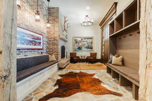 Spacious mudroom featuring flagstone flooring, a large brick fireplace, built-in bench seating, and an integrated wood-finish storage system with cubbies and hooks