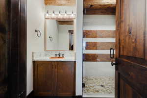 Bathroom vanity with a wood-finish cabinet, stone countertop, and vessel sink