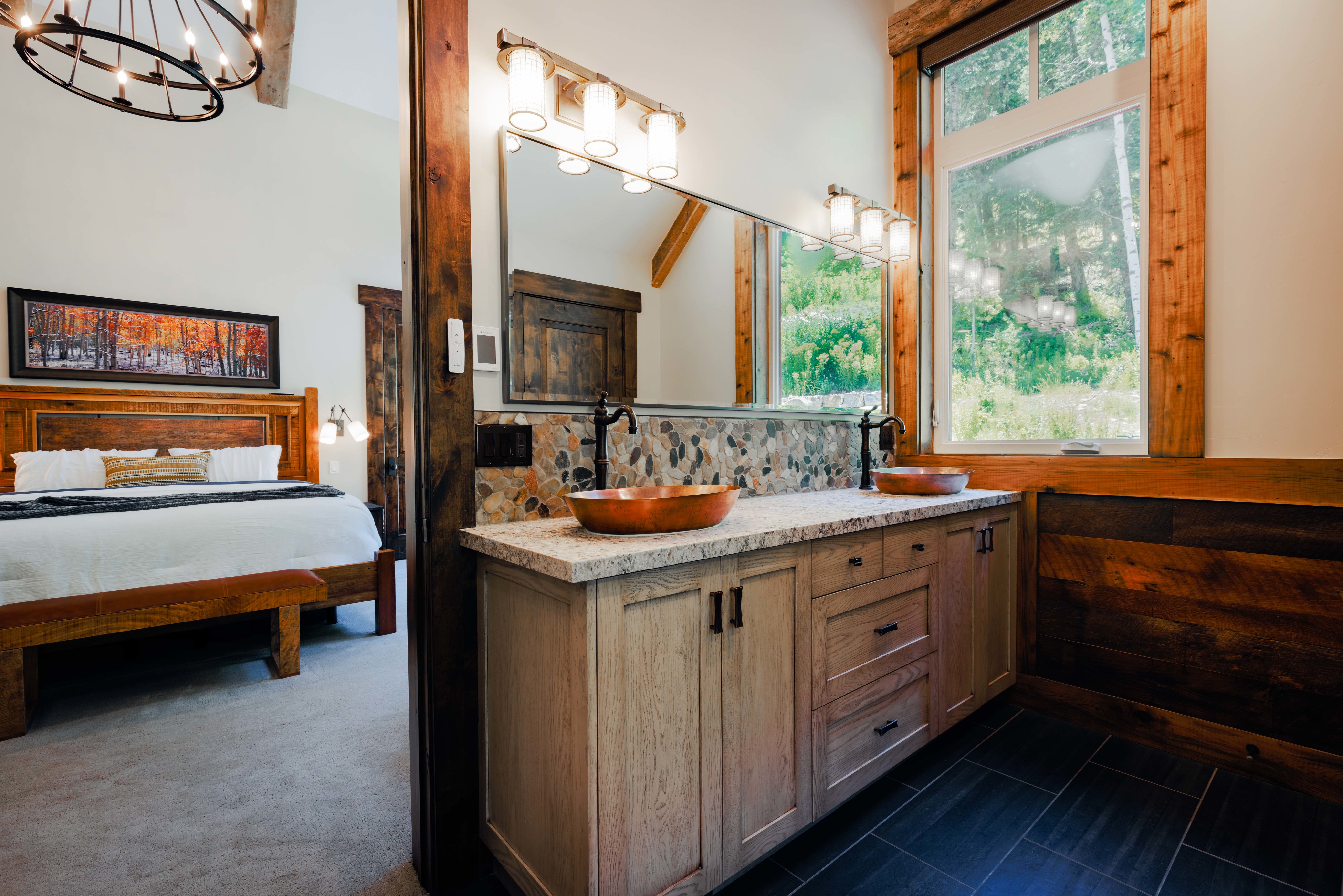 Double vanity featuring copper vessel sinks, matte black fixtures, stone tile backsplash, and a light-toned countertop