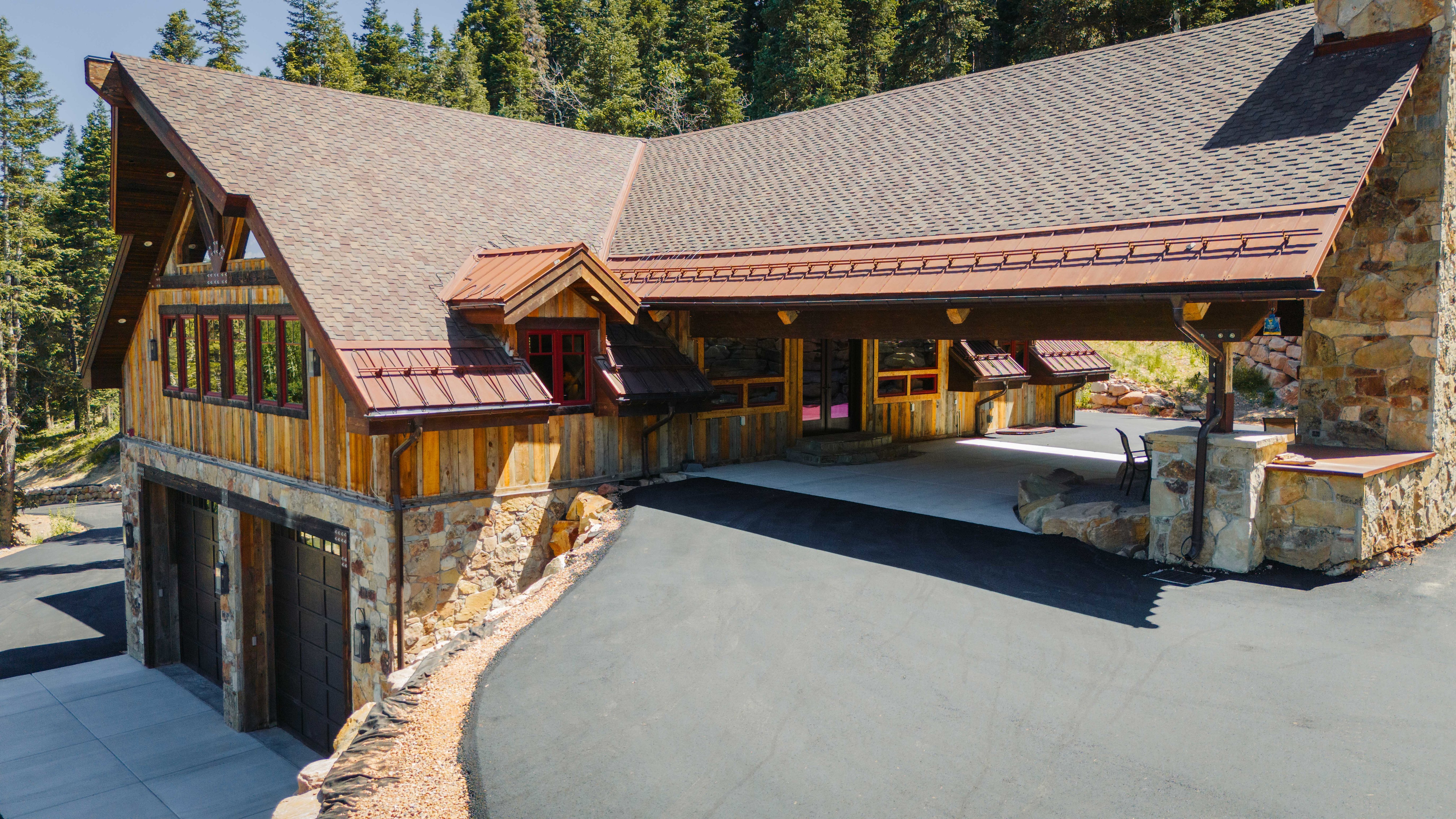 Rustic-modern exterior featuring natural wood siding, stone veneer accents, and a shingle roof with copper-toned metal details