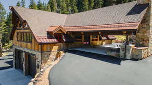 Rustic-modern exterior featuring natural wood siding, stone veneer accents, and a shingle roof with copper-toned metal details