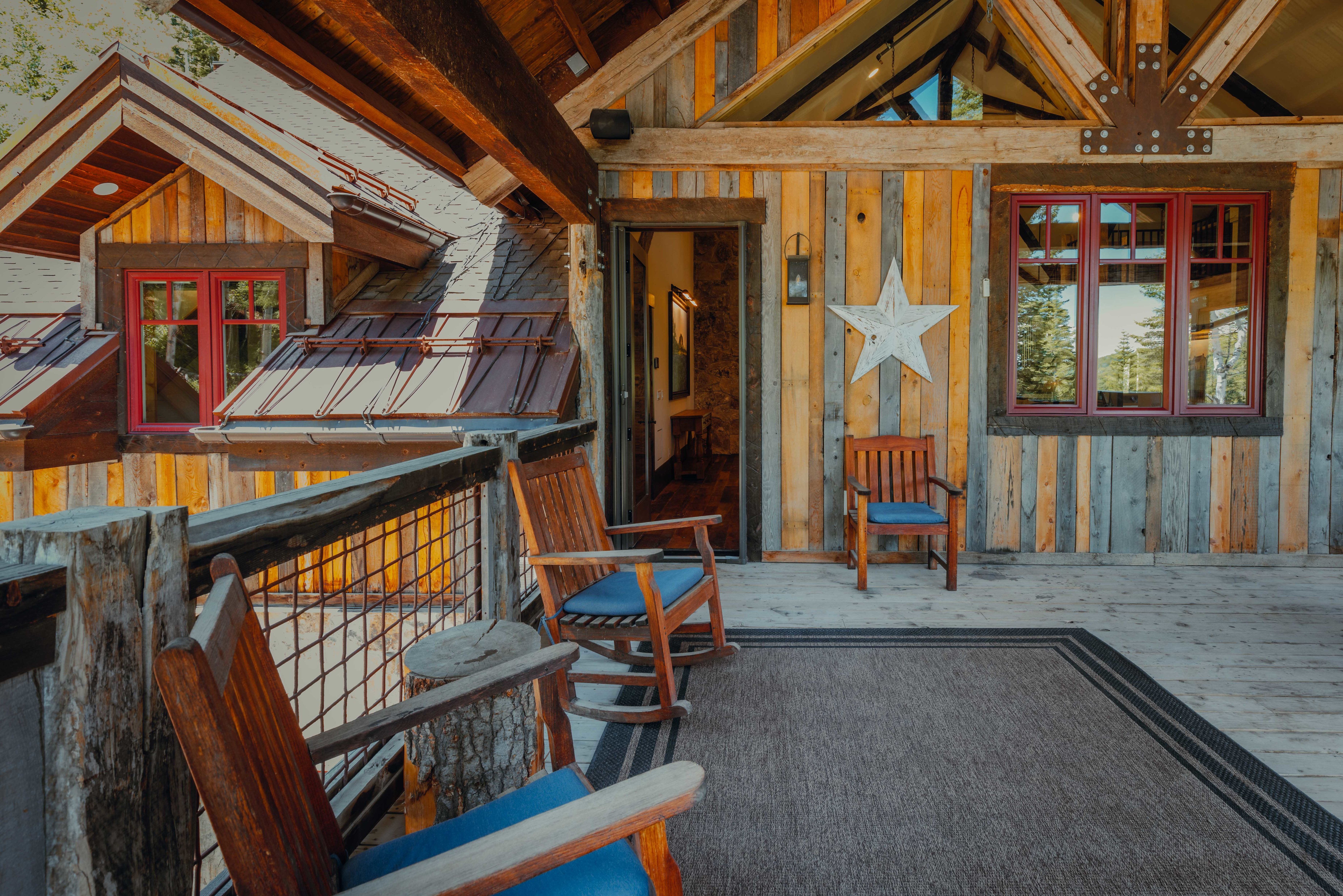 Expansive outdoor deck featuring wood-plank flooring, a wood and wire railing, and exposed ceiling beams