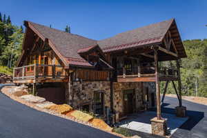 Rustic-modern residence featuring a stone and wood facade, a covered carport, and multiple balconies