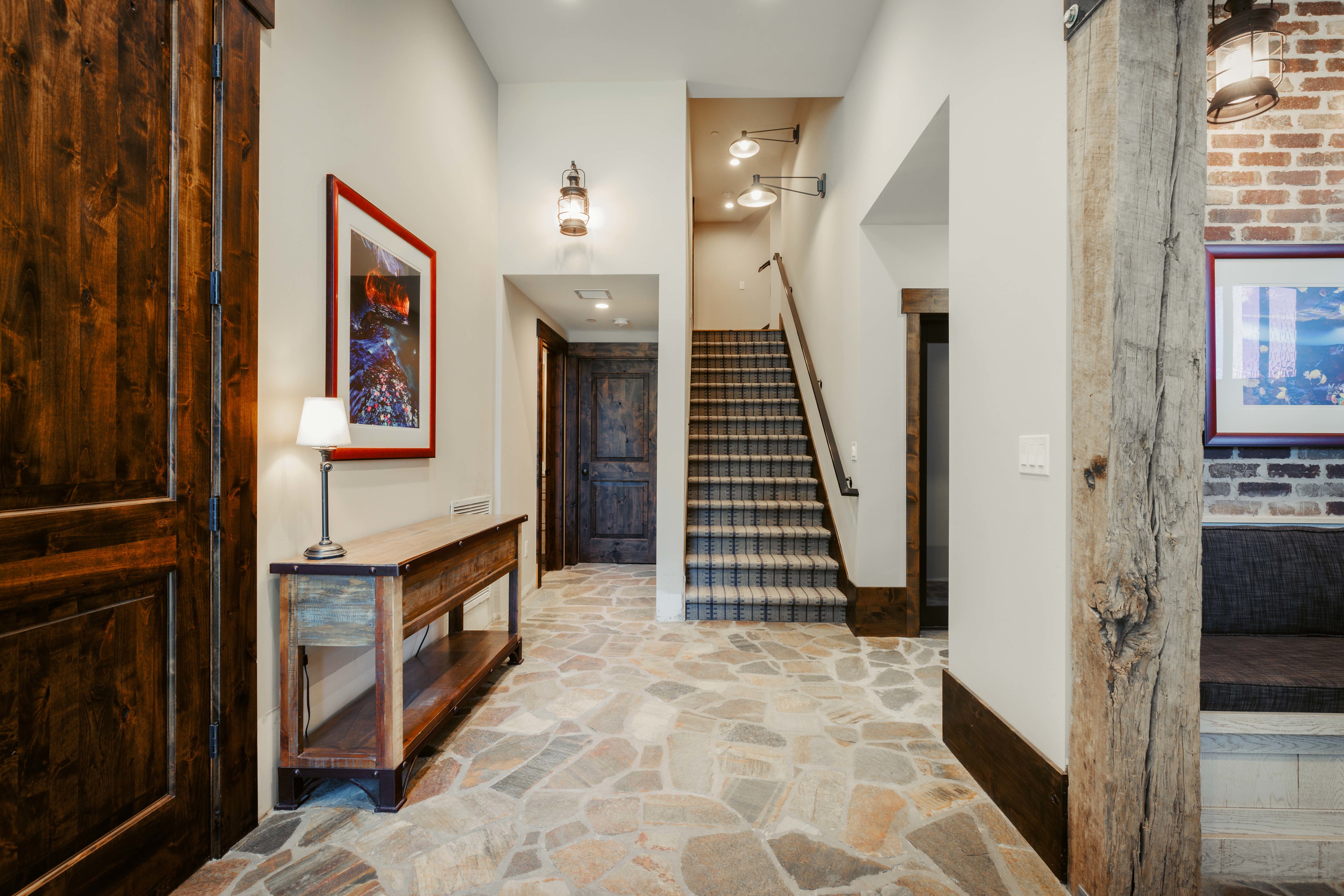 Entryway featuring irregular flagstone flooring, a dark wood barn door, and a staircase with patterned carpet