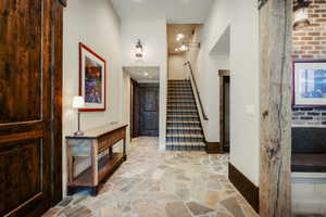 Entryway featuring irregular flagstone flooring, a dark wood barn door, and a staircase with patterned carpet