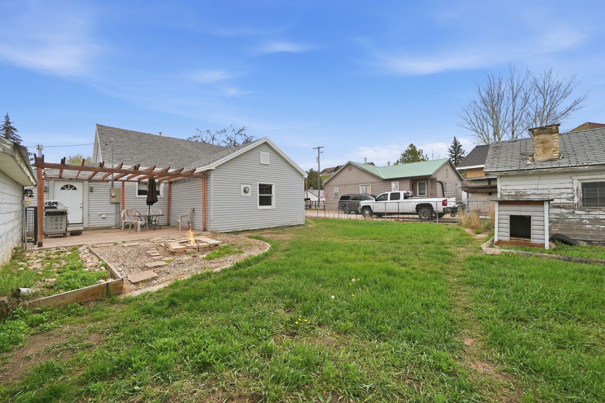 Rear exterior with light gray siding and an attached wood pergola over a patio