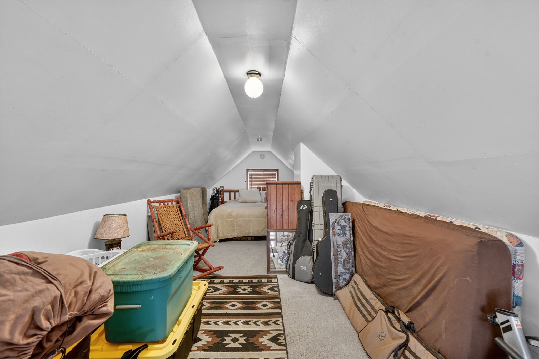 Attic space featuring sloped ceilings, a recessed window, and light carpeting