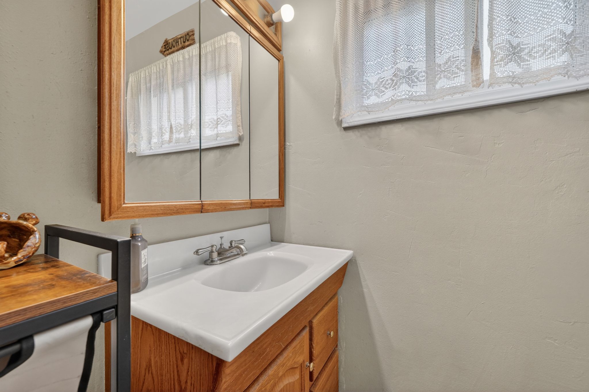 Bathroom vanity featuring a wood-finish cabinet, integrated white sink, and chrome faucet