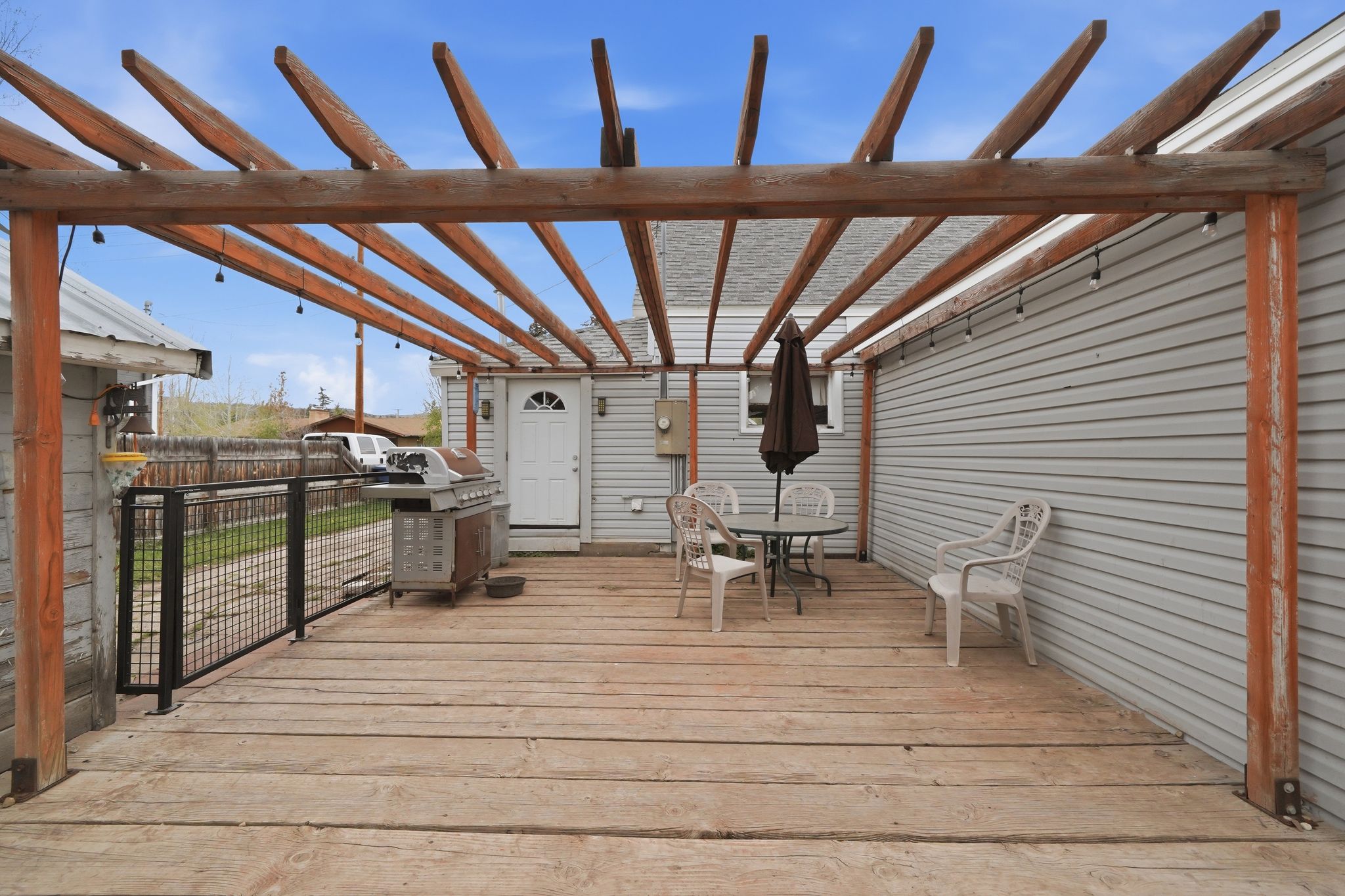 Expansive wood deck with a full-length pergola structure and integrated string lighting