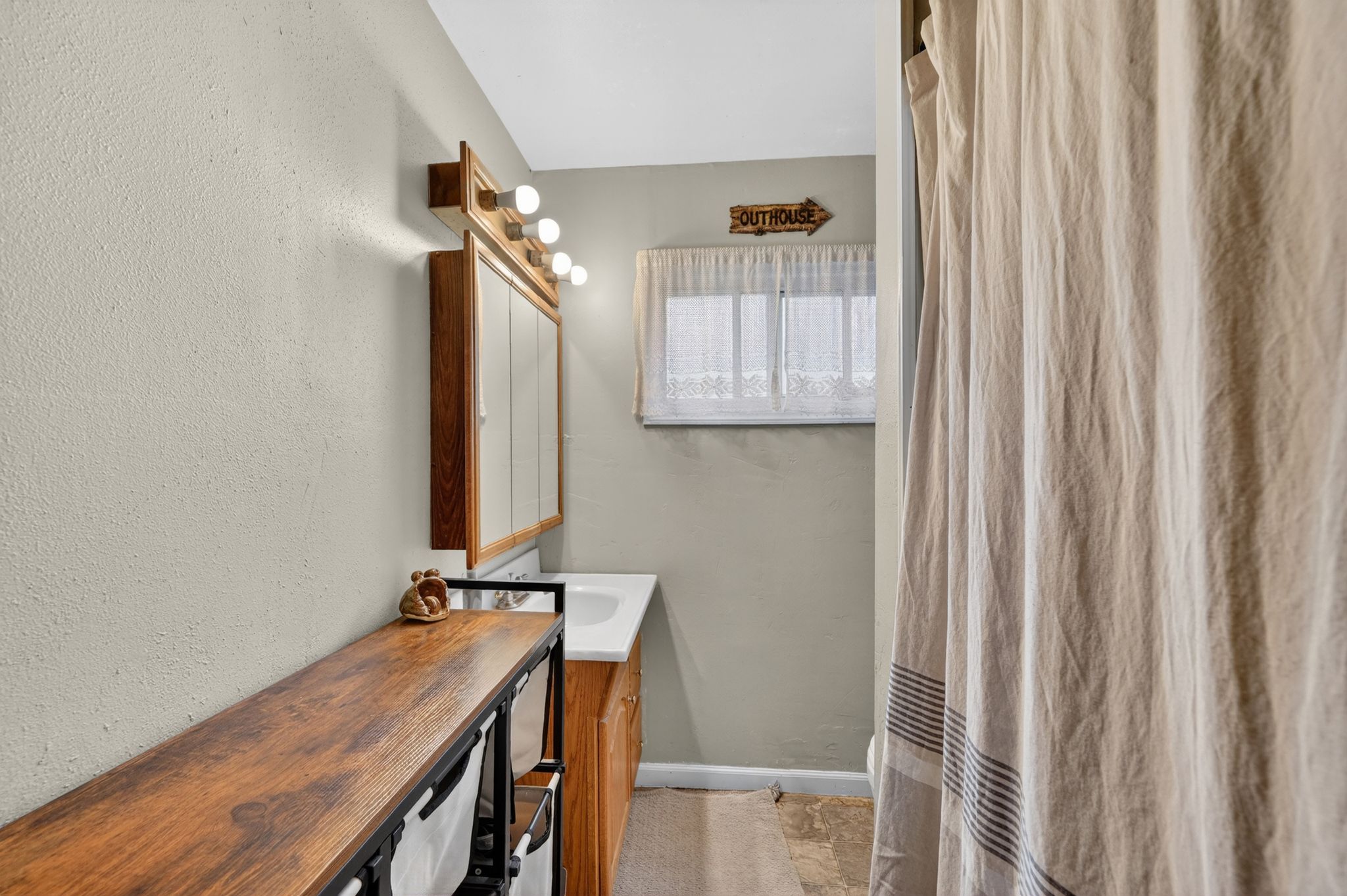 Bathroom featuring a vanity with a white basin and wood-finish cabinetry, a built-in medicine cabinet with integrated lighting, and textured walls