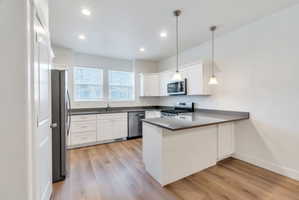Kitchen featuring white shaker cabinetry, stainless steel appliances, wood-finish flooring, recessed lighting, and pendant lighting