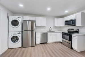 Modern kitchen space featuring white cabinetry, light-toned countertops, and wood-finish flooring