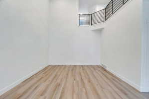 Spacious living area featuring light wood-finish flooring and crisp white walls