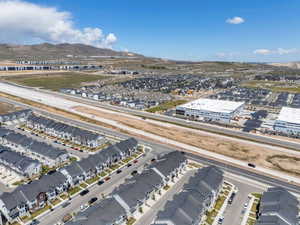 Expansive aerial showcasing a developing residential area with rows of multi-story townhomes, adjacent to a major roadway