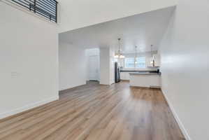 Open-concept living space featuring wood-finish flooring, white walls, and a modern kitchen