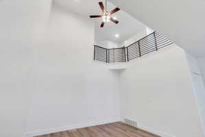 Two-story living area featuring a vaulted ceiling and a ceiling fan with integrated lighting