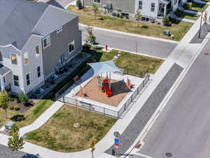 Community park area featuring a playground with a shade structure, wood chip base, and perimeter fencing