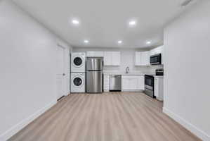 Open-concept kitchen area featuring light wood-finish flooring, white cabinetry, and stainless steel appliances
