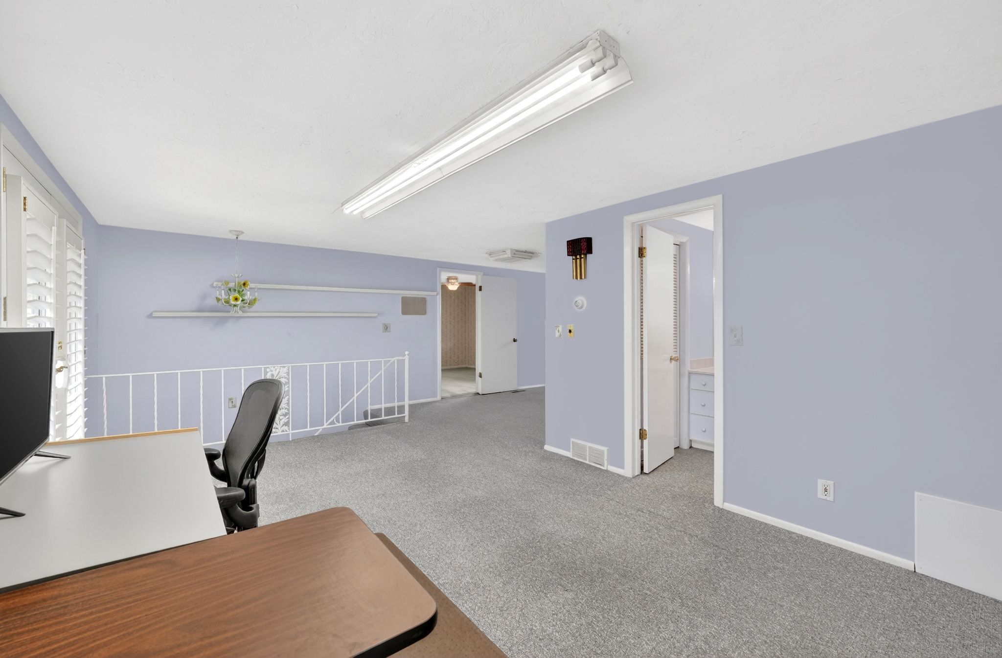 Spacious interior room featuring light blue walls and gray carpeting