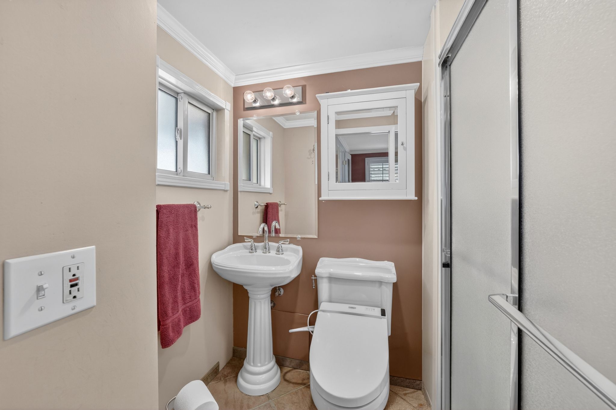Pedestal sink with chrome fixtures, mirrored medicine cabinet, and contemporary vanity lighting