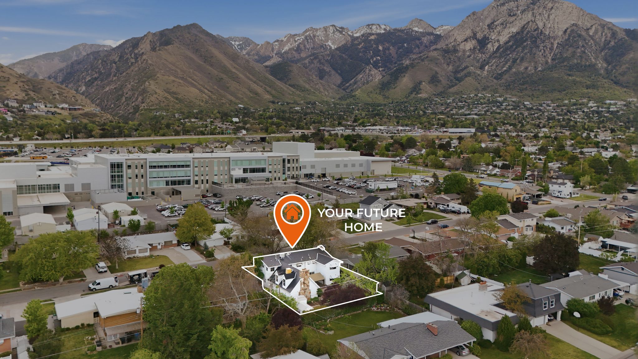 Aerial perspective highlighting the property with surrounding residential structures and distant mountains