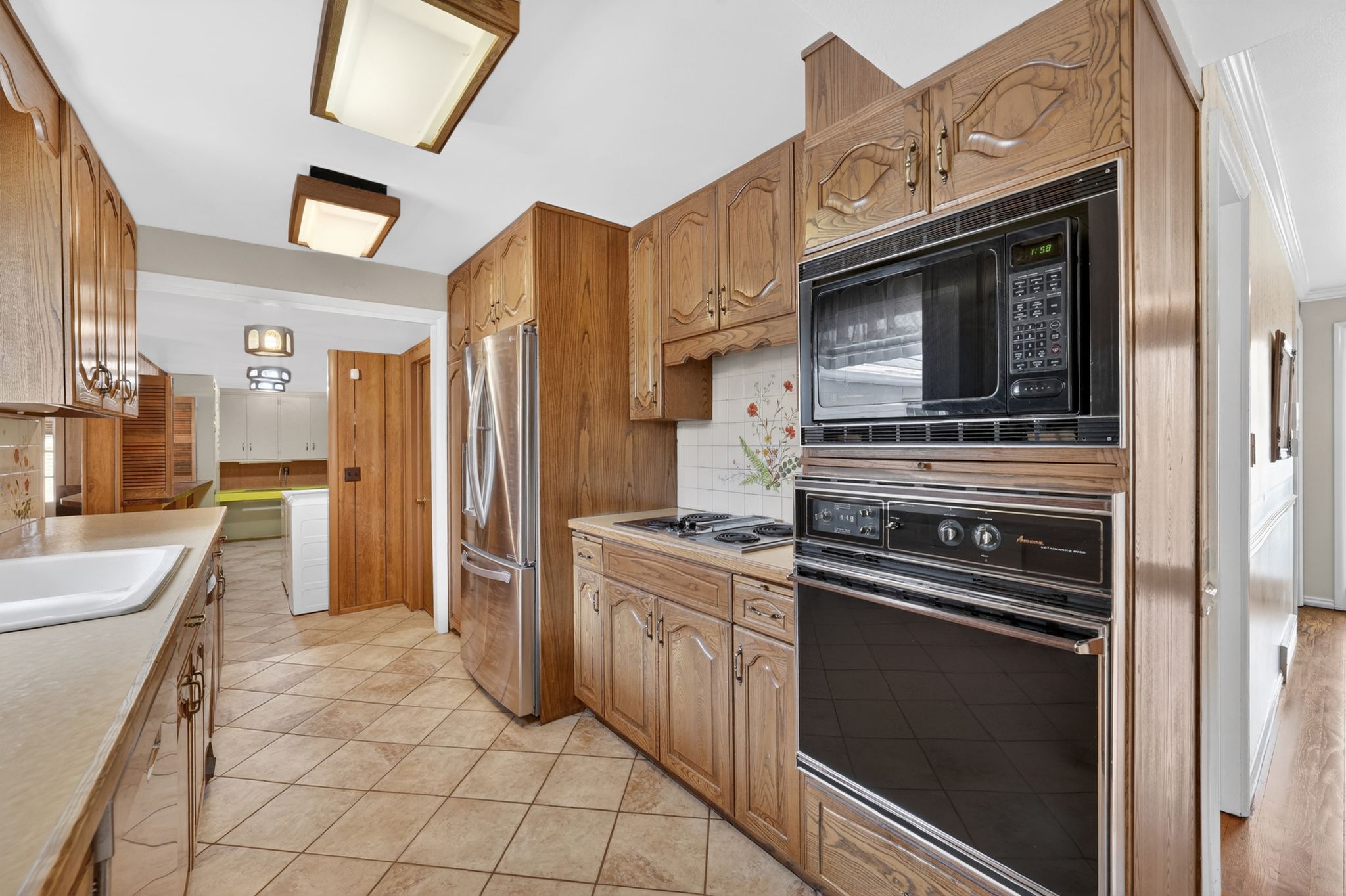 Kitchen featuring wood-finish cabinetry with decorative molding, ceramic tile flooring, and integrated wall oven with microwave