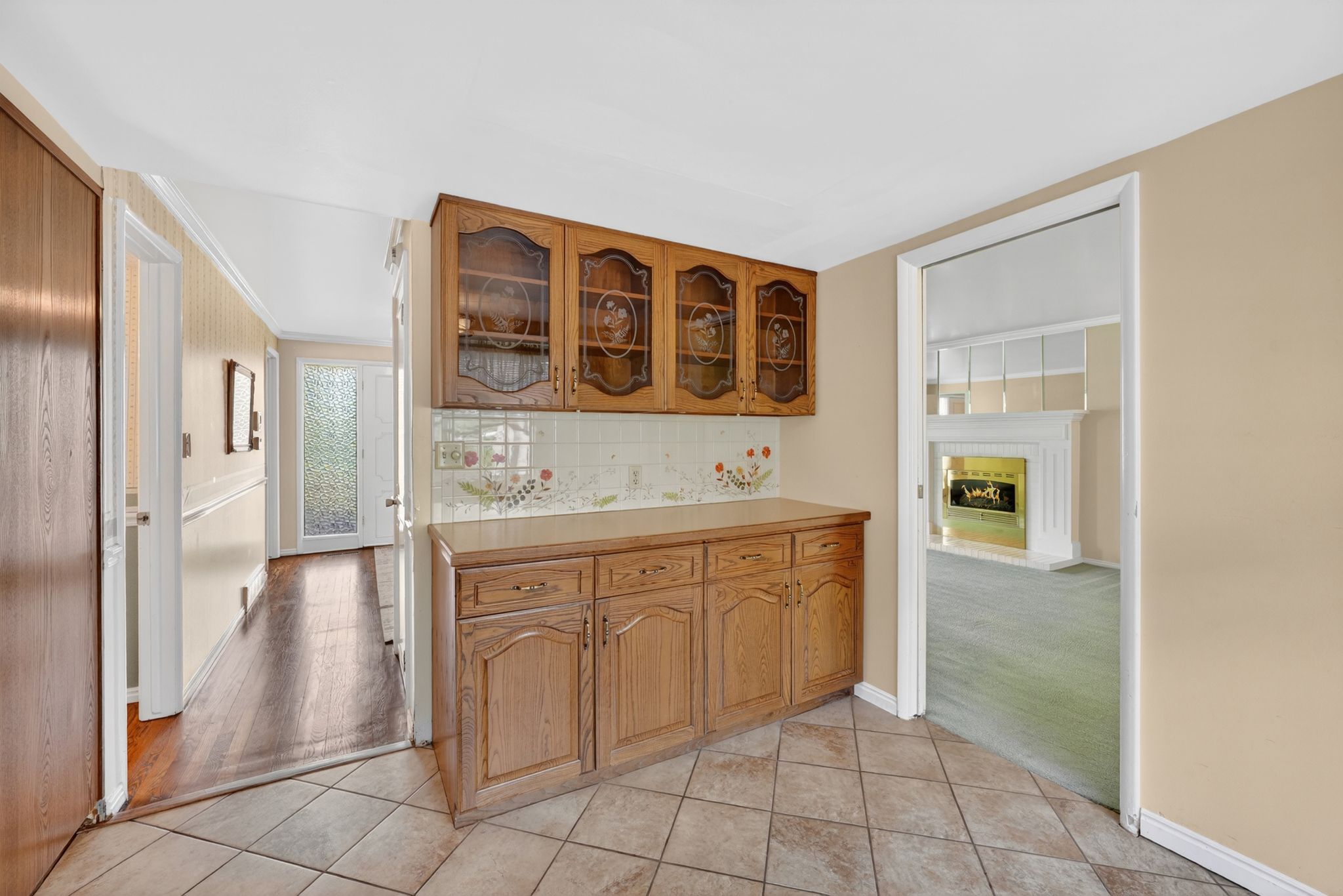 Built-in cabinetry with glass-front upper cabinets and wood-finish lower cabinets, complemented by a tiled backsplash and countertop