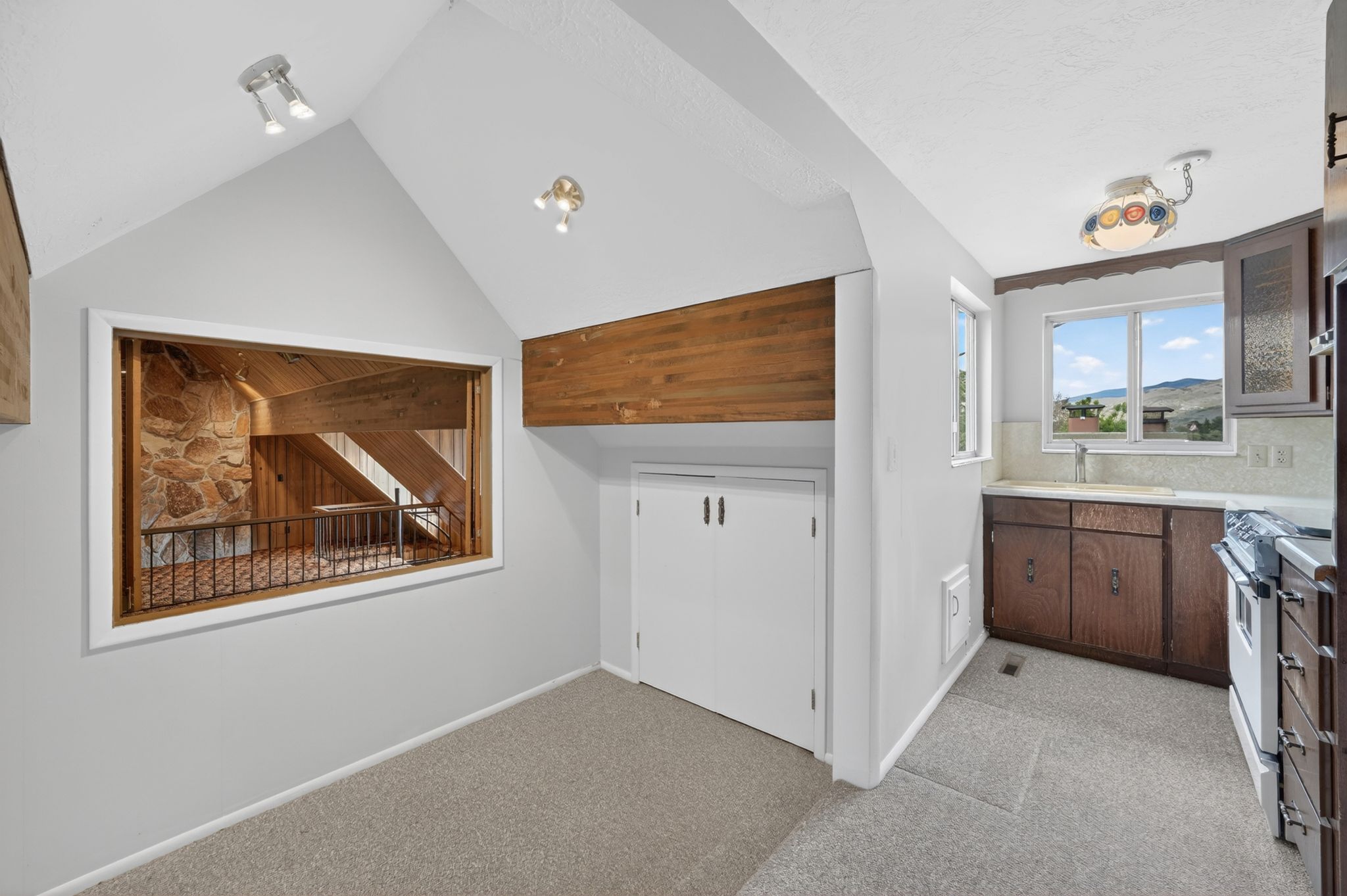 Kitchen area featuring wood cabinetry, a white gas range, and a dual-pane window above the sink