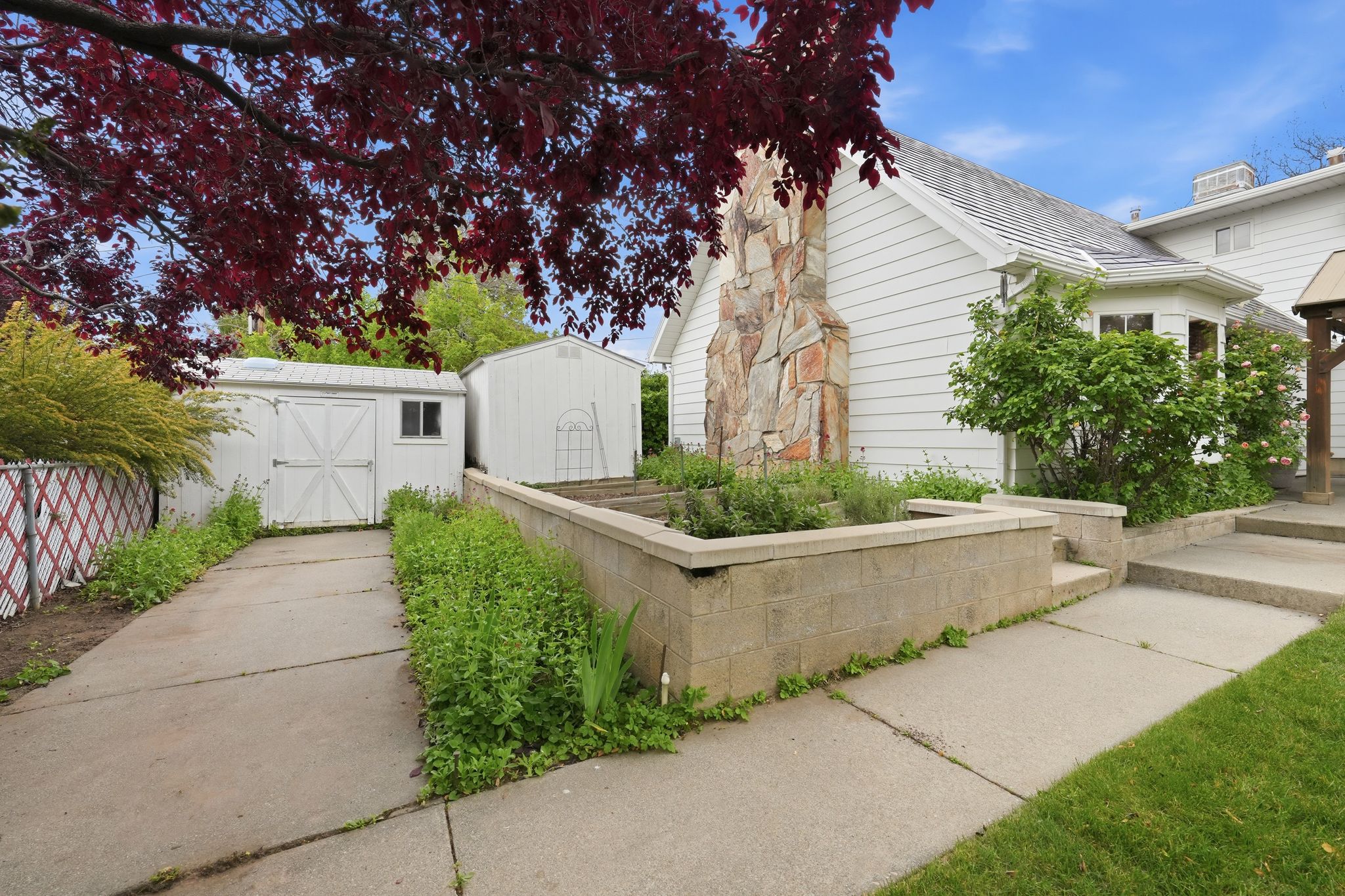 Siding exterior with a stone chimney feature, a bay window, and a concrete pathway