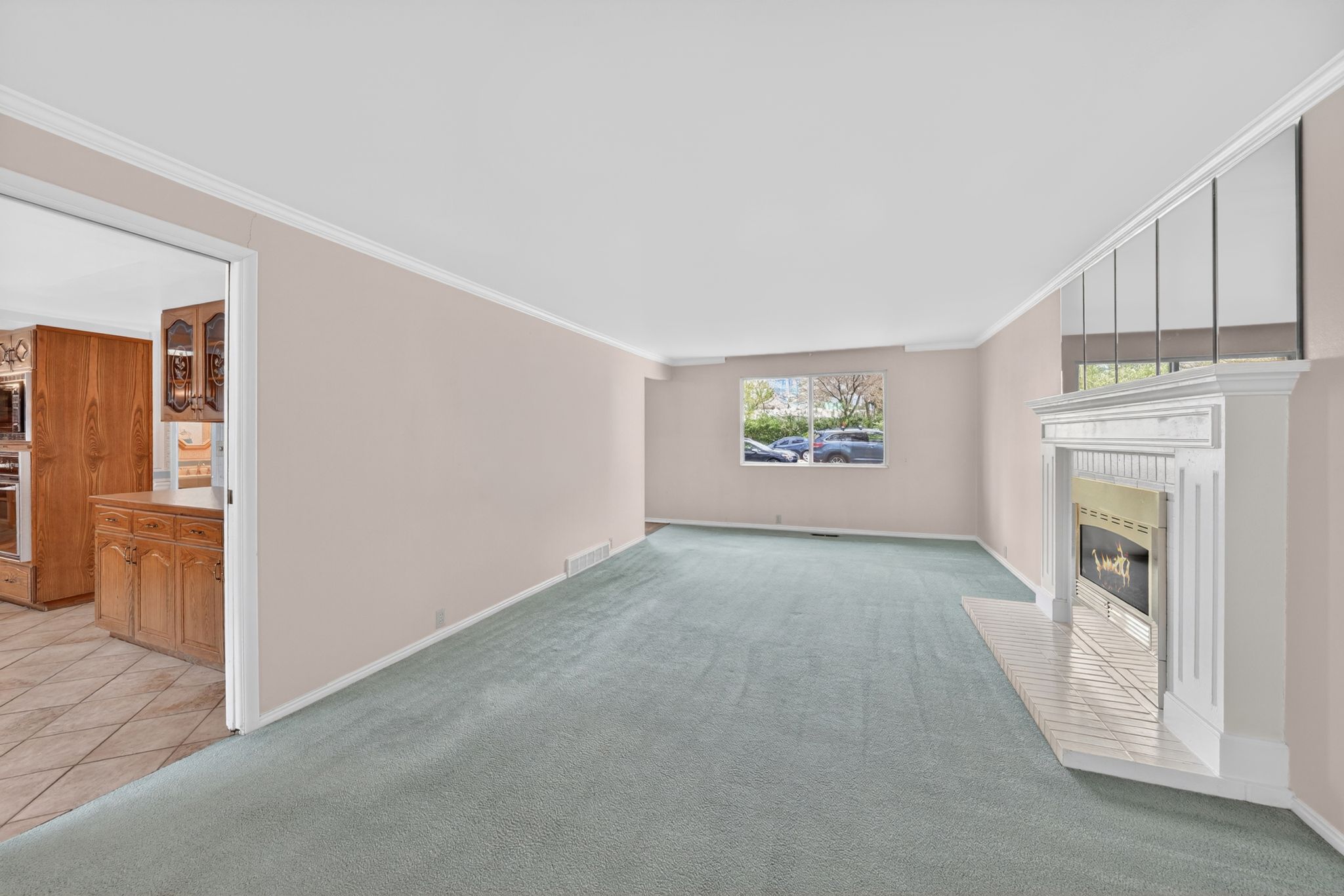 Spacious living area featuring light-colored walls, crown molding, and light blue carpeting