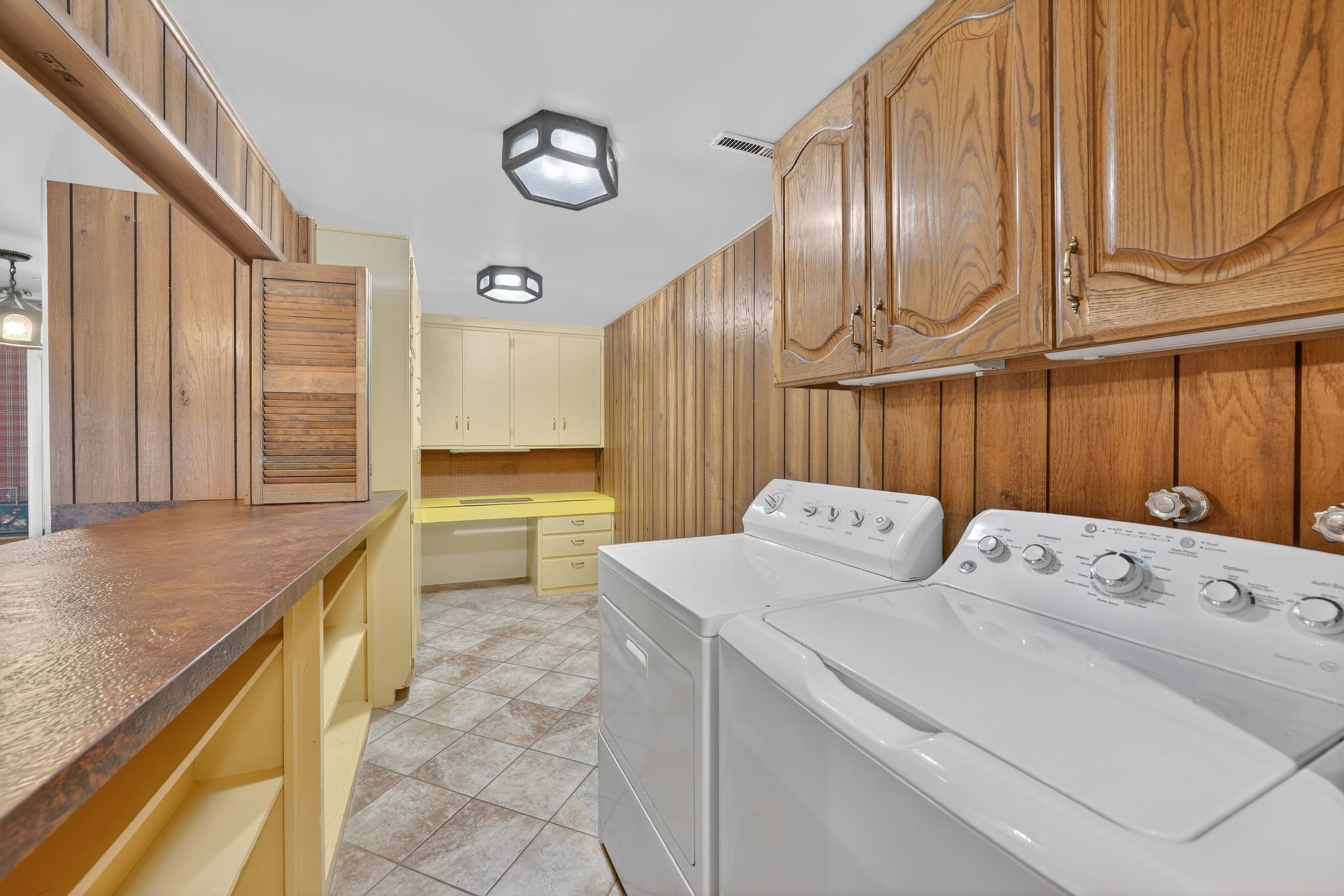 Laundry room featuring wood paneling, overhead cabinetry, and tile flooring