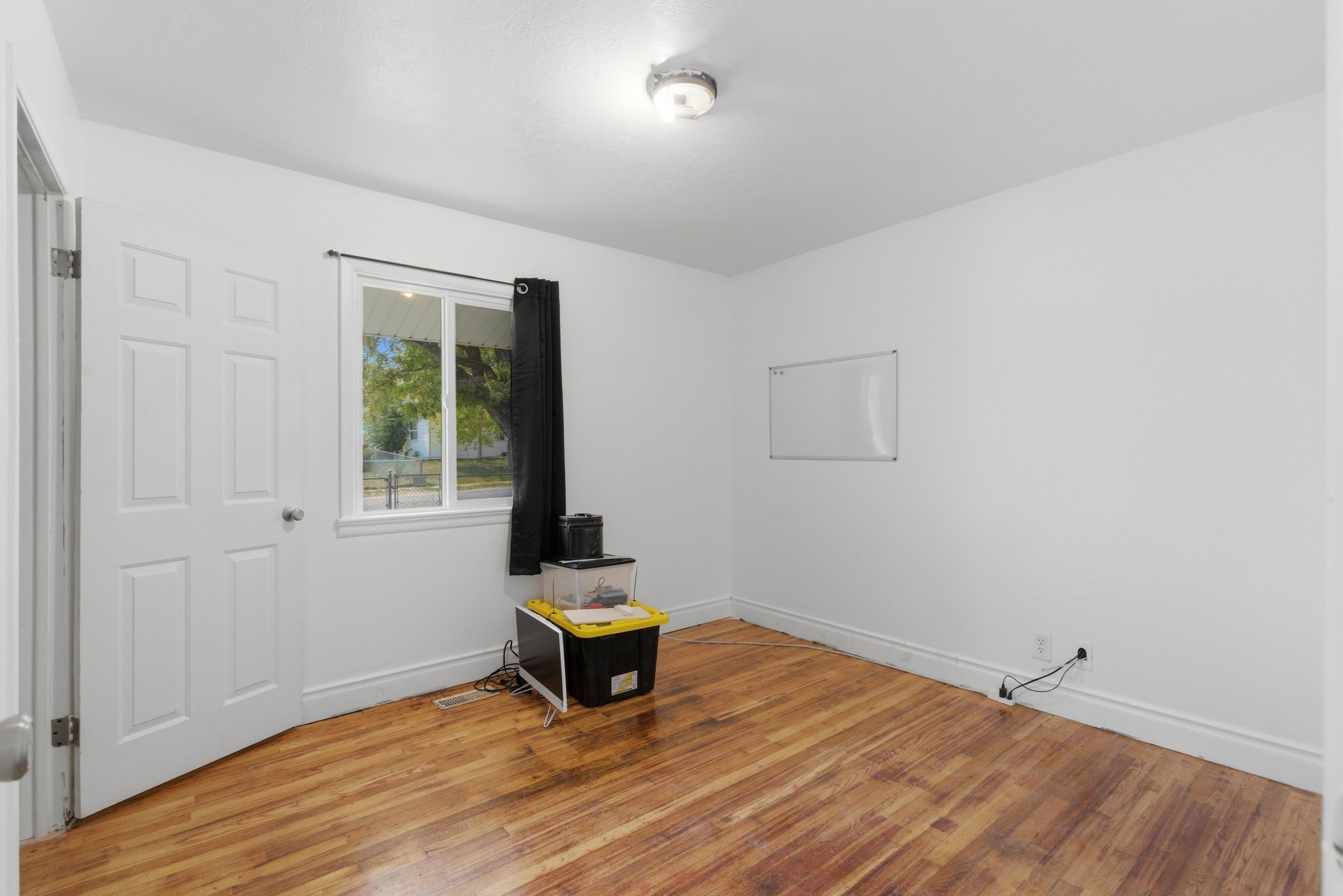 Room with wood-finish flooring, white walls, and a multi-pane window