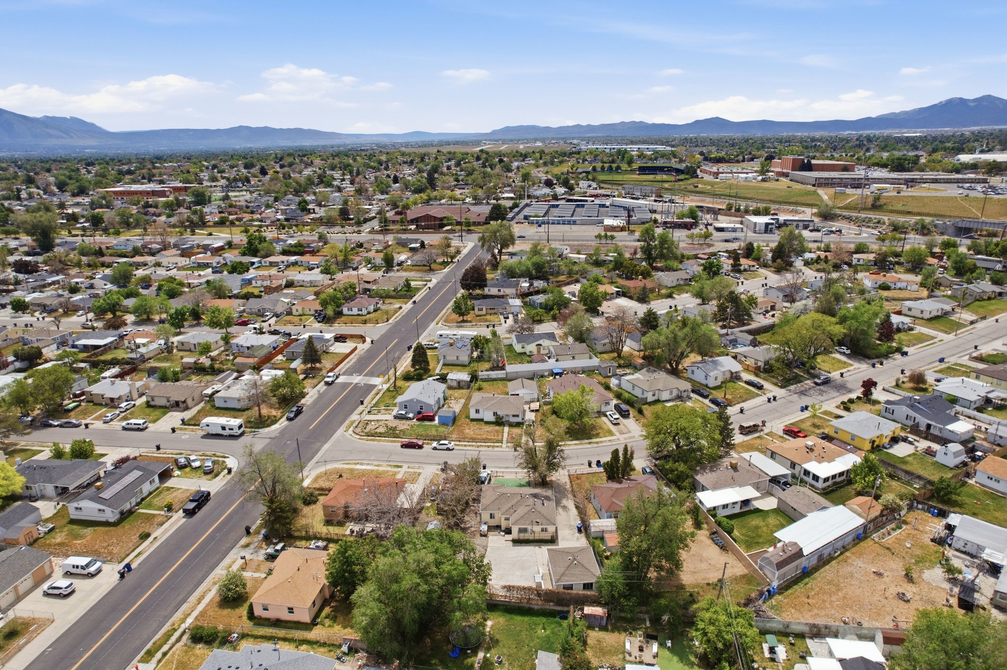 Aerial perspective showcasing a residential neighborhood with established homes, tree-lined streets, and distant mountain ranges